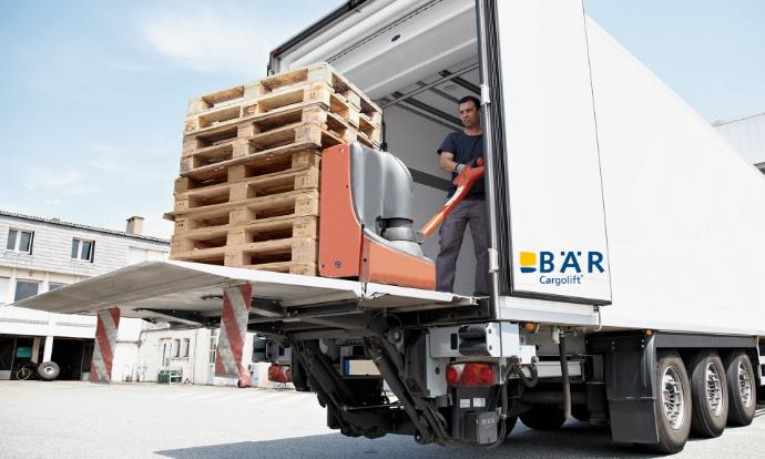 Otwarty i chowany pod nadwoziem podest załadowczy BAR, na którym osoba wsuwa pustą paletę do pojazdu.