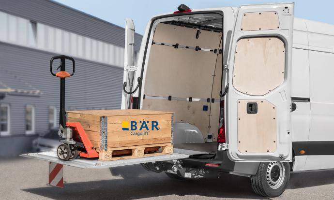 Paleta z wózkiem paletowym stoi na rozłożonej, podniesionej platformie Bar VanLift