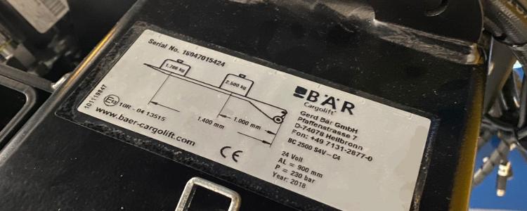 Tabliczka znamionowa windy załadowczej Bar Cargolift BC 2500 S4V -C4 przyklejona do rury nośnej